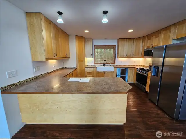 A large spacious and open kitchen takes advantage of a large breakfast bar and flexibility of entertaining.  It also takes in the magnificent views of the Hood Canal and Olympics through the soaring living room windows!  Note the under cabinet lighting adding utility and ambiance to the kitchen area. The Dishwasher is a two level unit to accomodate large or small loads.