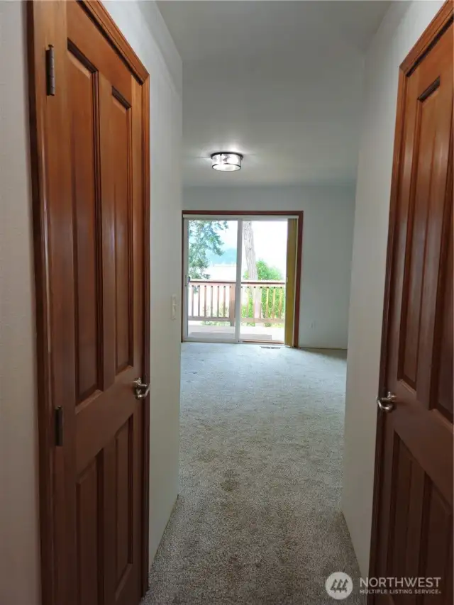 Looking from the ensuite bath out to the primary  suite sliding glass doors that lead to a private deck and stairs to a private side yard area.  All of this is on the view side of the home and takes in the magnificent Hood Canal and the towering Olympic Mountain Range.