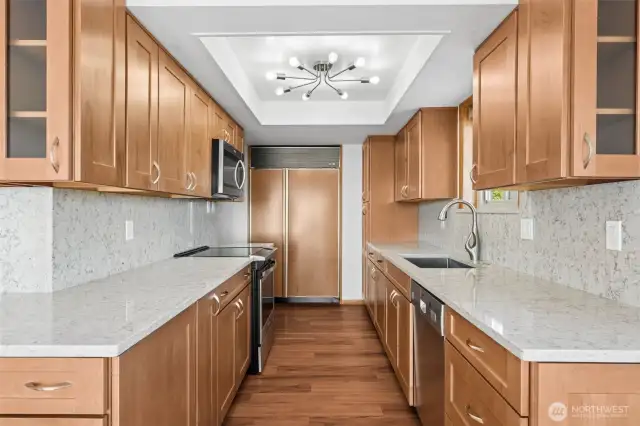 Updated kitchen with Sub-Zero refrigerator, new stove, quartz counters, and modern lighting.