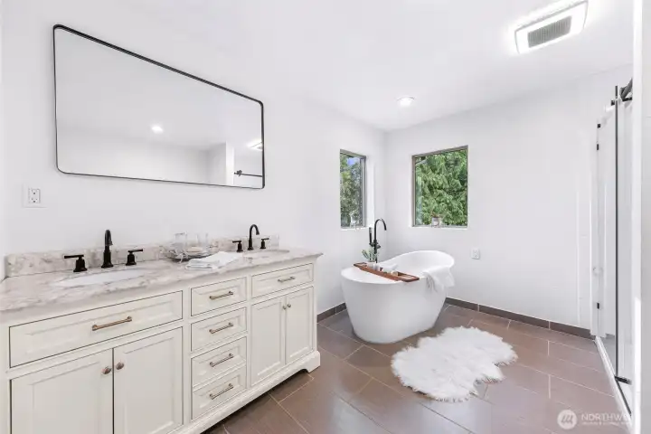 Primary bath has separate soaking tub and shower, two sinks. Distinctive tile floors.