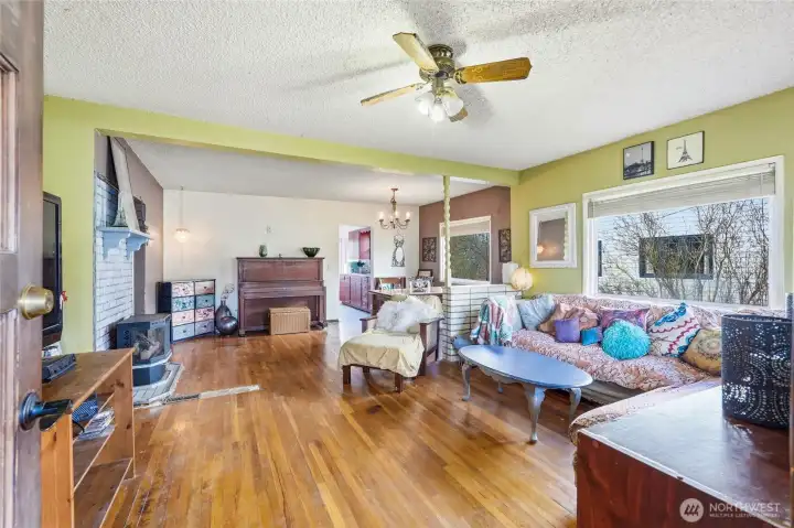 An expansive open-concept living area boasts hardwood floors, a gas fireplace, and a large picture window that floods the space with natural light.