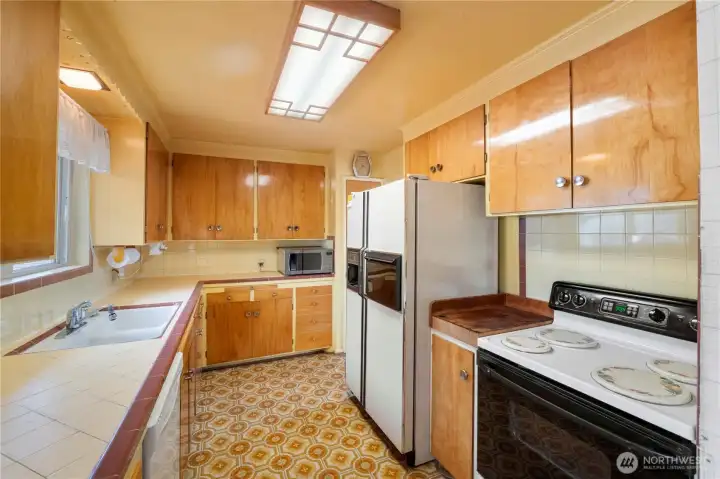 Galley kitchen butcher block countertop next to stove.