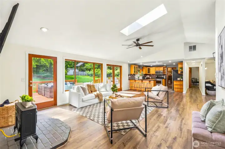 Open-concept great room with vaulted ceilings, skylights, oversized windows, and seamless access to the deck and backyard.