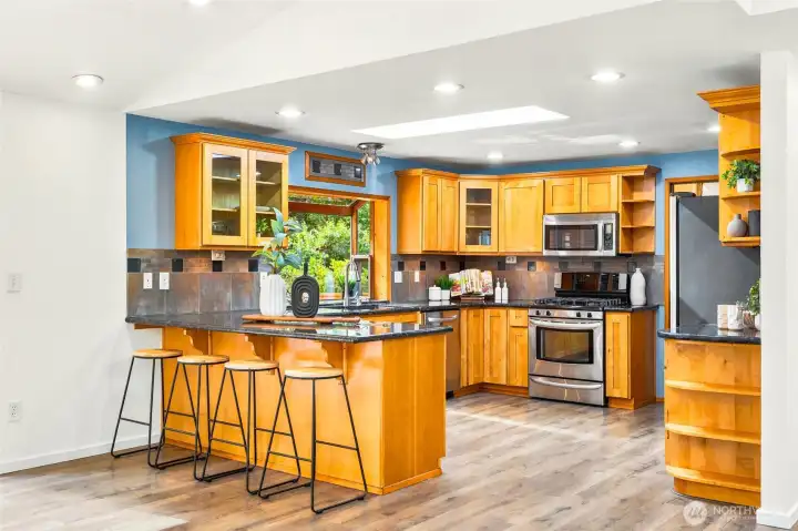 Spacious kitchen featuring granite countertops, stainless steel appliances, abundant cabinetry, and a large eating bar with seating for four.