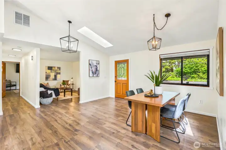 Light-filled dining area featuring a skylight, large picture window, and seamless flow to the kitchen and living spaces.