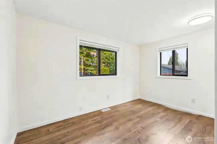 Light-filled bedroom with fresh paint and new laminate flooring.