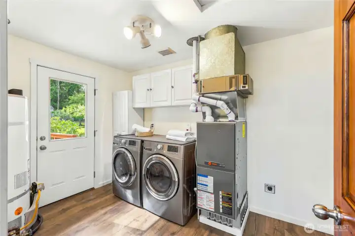 Spacious utility room with storage cabinetry, full-size laundry area, and convenient exterior access.