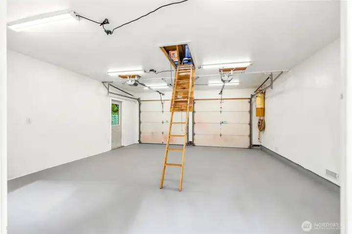 Spacious two-car garage offers epoxy flooring, pull-down attic storage, and abundant space for parking and projects