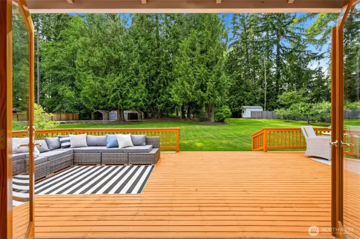 French doors open to an expansive entertaining deck, creating seamless indoor-outdoor living and overlooking the park-like backyard with mature trees, lush lawn, and exceptional privacy.