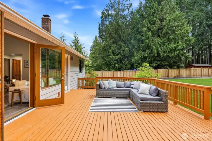 French doors open to an expansive entertainment deck, creating seamless indoor-outdoor living and the perfect setting for gatherings.