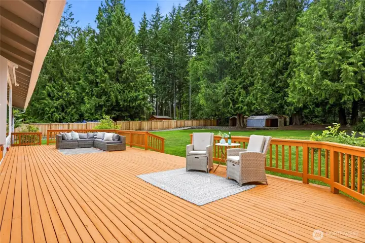 Oversized deck overlooks the private, park-like backyard, offering abundant space for outdoor dining, relaxing, and entertaining.
