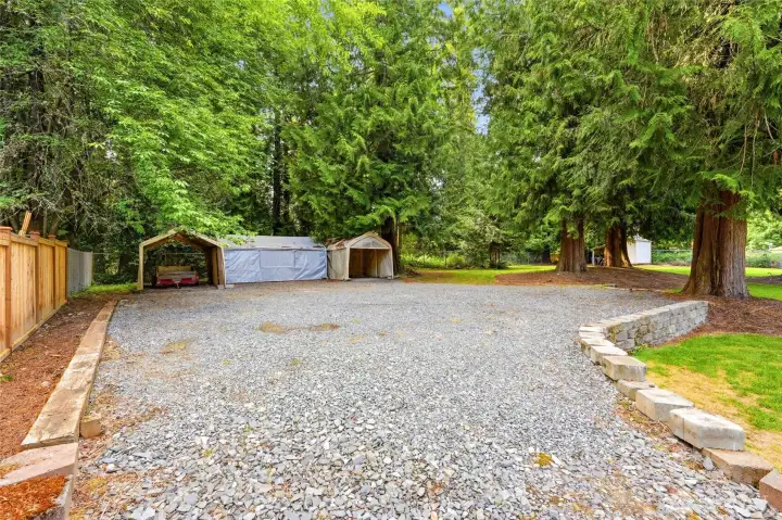 Generous graveled parking area with gated access offers exceptional space for RV parking, recreational vehicles, trailers, and more.