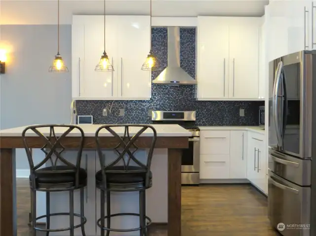 KITCHEN ALSO BOATS ISLAND SEATING BEAUTIFUL SPARKLING BACKSPLASH AND FULL SIZED HOODED FAN OVER THE PROPANE STOVE!