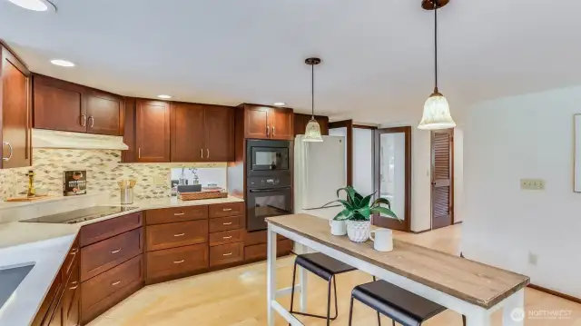 Warm cherry cabinetry and quartz counter add character to this large kitchen, complete with ample storage, counter space, and all appliances stay.