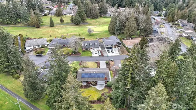 Aerial view of the home overlooking the darling cul de sac it sits on with views of the golf course behind the home, and more golf course just across the street.