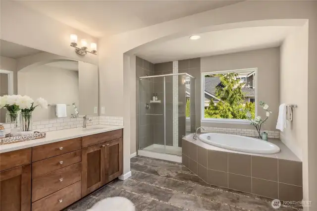 Dual sinks, a shower, soaking tub and ample cabinetry storage are in this space.