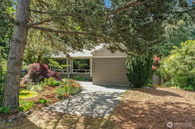 Beautiful setting with so many gorgeous plant, bushes and trees. EV charger just behind the bush on the right. Room for a carport.