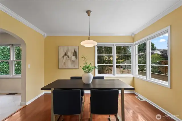 Formal dining room framed by big corner windows with a dreamy vintage light fixture