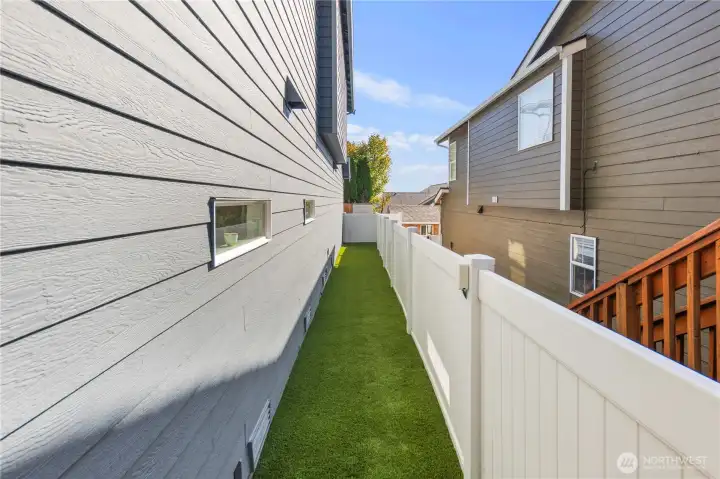 Fenced backyard with turf covering.