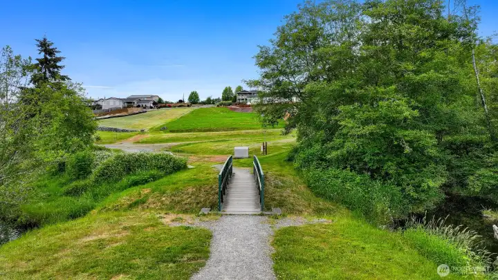 Well maintained strolling path includes this quaint footbridge. The property is ahead and to the left in this photo. Well maintained strolling path includes this quaint footbridge. The property is ahead and to the left in this photo.
