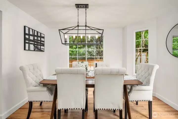 Elegant formal dining room featuring refinished hardwood floors, updated lighting, and large windows that flood the space with natural light. Elegant formal dining room featuring refinished hardwood floors, updated lighting, and large windows that flood the space with natural light.