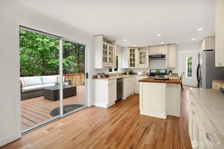 Spacious and well-appointed kitchen featuring ample white cabinetry, hardwood floors, and a slider to the deck, seamlessly blending indoor and outdoor living. Spacious and well-appointed kitchen featuring ample white cabinetry, hardwood floors, and a slider to the deck, seamlessly blending indoor and outdoor living.