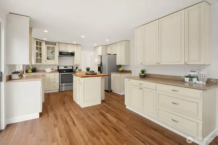 Generous kitchen layout showcasing abundant cabinetry, hardwood floors, and stainless steel appliances, offering both style and functionality for everyday living. Generous kitchen layout showcasing abundant cabinetry, hardwood floors, and stainless steel appliances, offering both style and functionality for everyday living.
