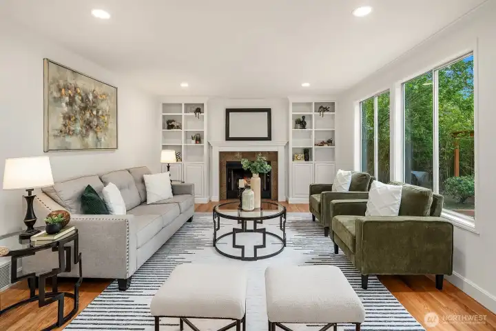 Warm and inviting family room featuring a gas fireplace with built-in shelving, hardwood floors, and large windows that bring the outdoors in. Warm and inviting family room featuring a gas fireplace with built-in shelving, hardwood floors, and large windows that bring the outdoors in.