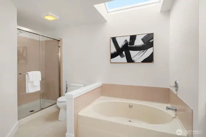 Another view of the primary ensuite highlighting the skylight, soaking tub, and separate shower, creating a bright and spa-like bathing experience. Another view of the primary ensuite highlighting the skylight, soaking tub, and separate shower, creating a bright and spa-like bathing experience.