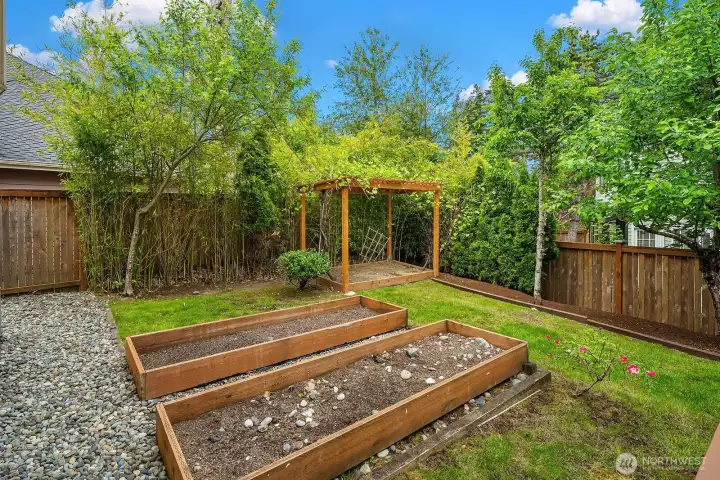 Charming backyard featuring raised planter boxes, a classic pergola, and fully fenced surroundings, offering the perfect setup for gardening enthusiasts and outdoor enjoyment. Charming backyard featuring raised planter boxes, a classic pergola, and fully fenced surroundings, offering the perfect setup for gardening enthusiasts and outdoor enjoyment.