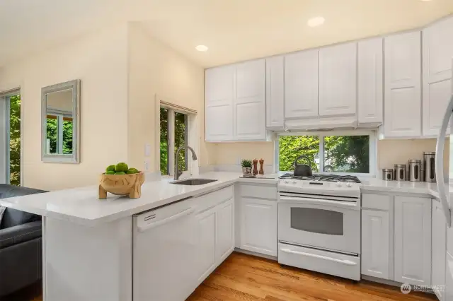 The kitchen has quartz counters, gas cooktop, white-on-white appliances and cabinets that reach the ceiling.