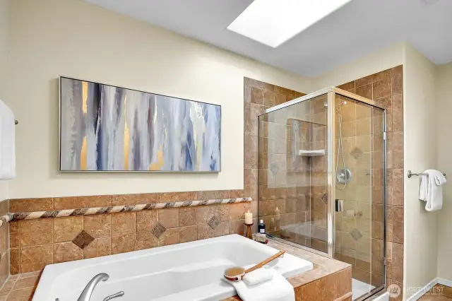 A skylight, soaker-tub, double-sinks and bench turn this en-suite primary bathroom into a spa.
