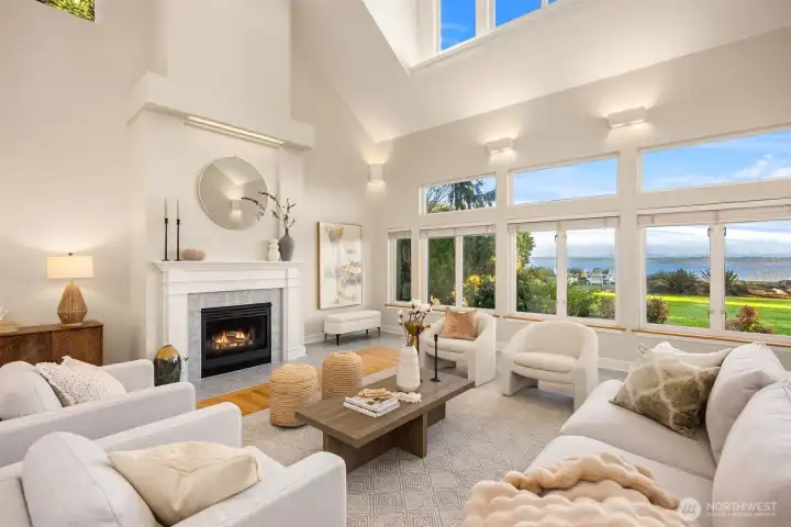 Vaulted ceilings, gas fireplace, and expansive windows showcase the water view and create a bright, open main living space.