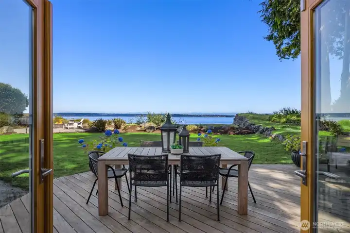 Outdoor dining area on back deck overlooking the lawn and expansive water views, with direct access from the dining room & kitchen areas for easy indoor-outdoor living.