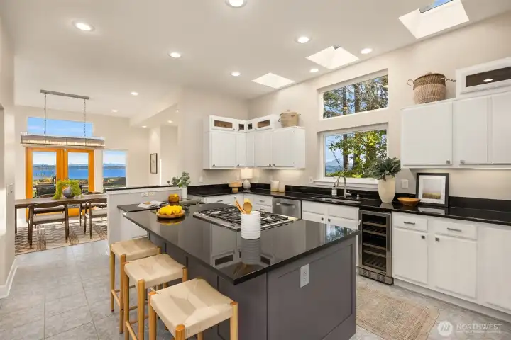 Open kitchen with large island, gas cooktop, skylights, and ample cabinetry, positioned to capture natural light and water views.