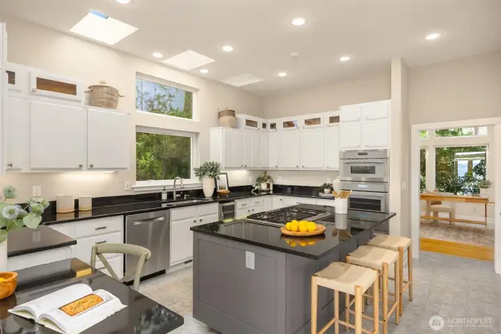 Bright kitchen with skylights, extensive cabinetry, double ovens, gas cooktop and a large island with room for seating - offering ample workspace and storage. Door leads into what is technically the third bedroom. Can also be used as an office or flex space.