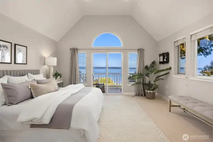 Primary bedroom with vaulted ceilings, private deck access, and expansive water views, creating a bright and spacious retreat.