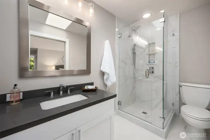 Ensuite bathroom featuring a walk-in glass shower with tile surround, modern vanity, and updated fixtures.