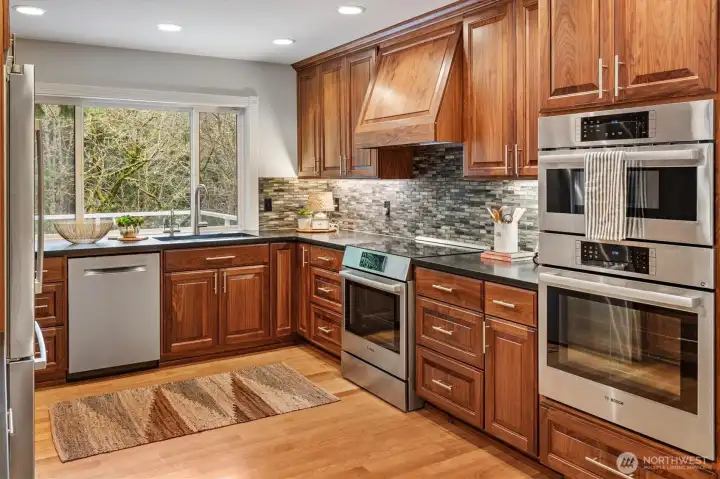 This gorgeous kitchen black quartz countertops, all Bosch appliances, an induction stove and hooded vent, backsplash throughout. Not to mention the large picture window overlooking the back of the property.