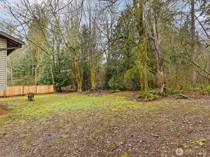 A spacious, partially fenced backyard with a creekside setting provides room to create your ideal outdoor space.