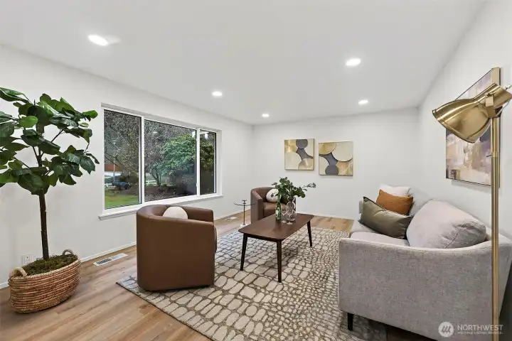 A bright, well-proportioned living room with a large picture window overlooking the treed yard, recessed lighting, and easy flow to the rest of the home.