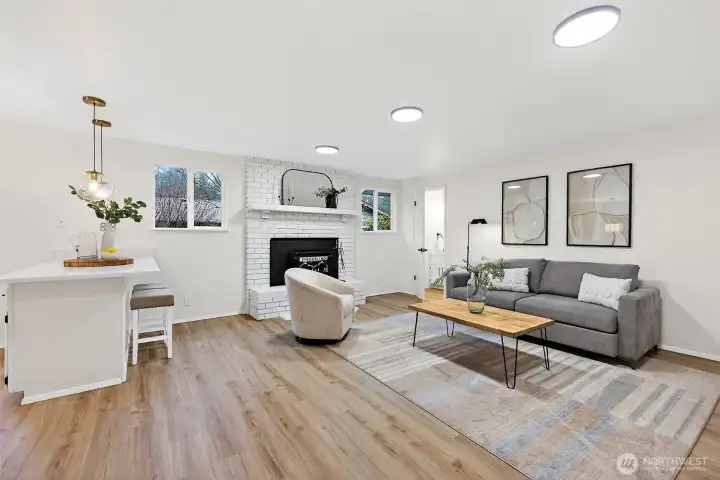 The heart of the home features a painted white brick fireplace, LVP flooring, and a seamless connection to the kitchen bar — ideal for everyday living and entertaining.