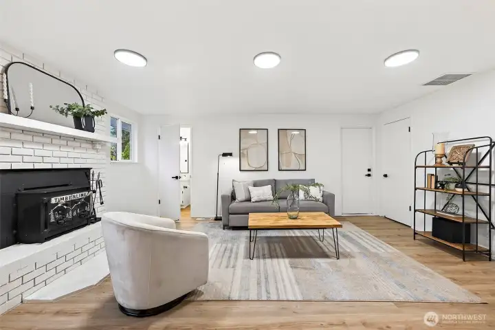 A second angle of the spacious family room highlights the brick fireplace as a focal point, with ample room for multiple seating arrangements.