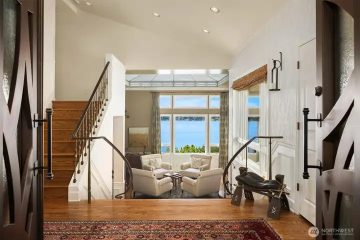 Grand entry that makes an unforgettable first impression—soaring ceilings, architectural detail, and a straight-on reveal to breathtaking lake views beyond.