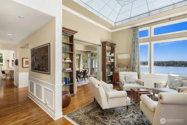 Light-filled living space with custom ceiling mural, built-in shelving, and seamless flow to dining—framed by Lake Washington views.