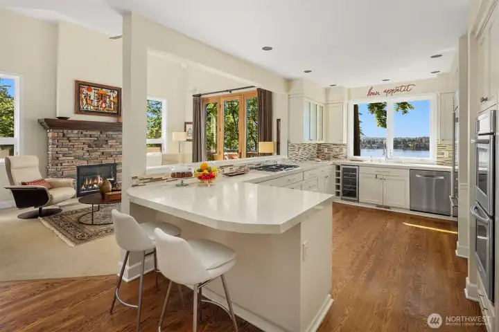 Open-concept kitchen and great room anchored by a generous island and fireplace, seamlessly extending to outdoor living with Lake Washington views.