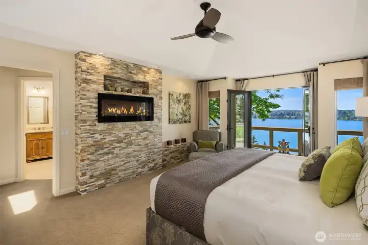 Primary suite retreat featuring a striking stacked-stone gas fireplace, private deck access, and seamless connection to a spa-inspired bath.