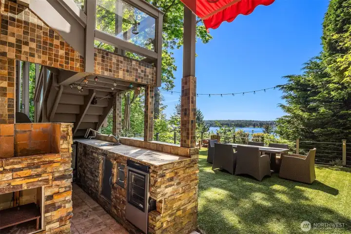 An outdoor kitchen and dining setting that invites everything outside—cook, gather, and linger with the lake as your backdrop.