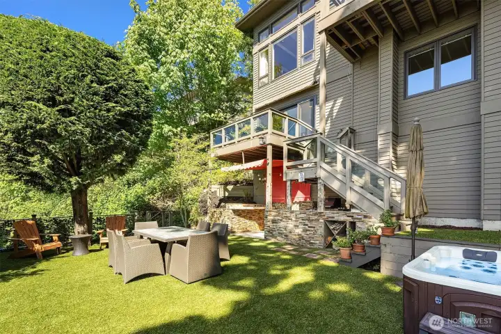 Private backyard retreat with layered entertaining spaces—from outdoor kitchen and dining to turf lawn and hot tub—all set within a lush, secluded setting. Designed for gathering, relaxing, and enjoying the outdoors at every turn.