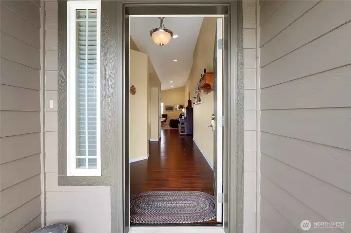 The entryway and hallway into the home features LVP flooring and a beautiful chandelier to welcome you in.